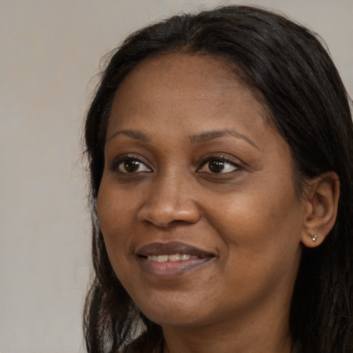 Joyful black adult female with long  brown hair and brown eyes