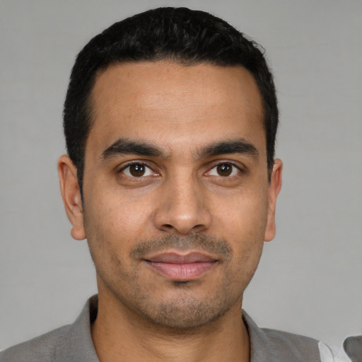 Joyful latino young-adult male with short  black hair and brown eyes