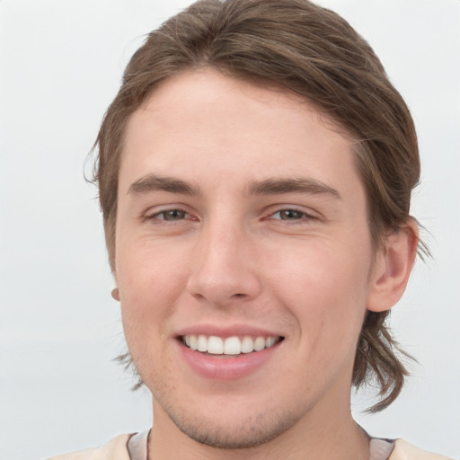 Joyful white young-adult male with medium  brown hair and grey eyes