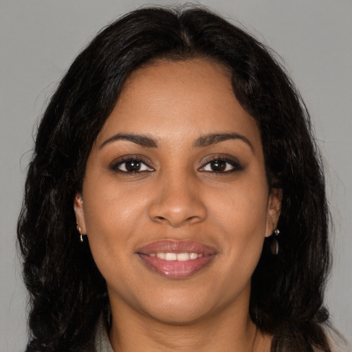 Joyful black young-adult female with long  brown hair and brown eyes