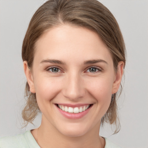 Joyful white young-adult female with medium  brown hair and grey eyes