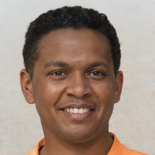 Joyful black young-adult male with short  brown hair and brown eyes
