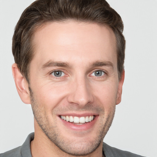 Joyful white young-adult male with short  brown hair and grey eyes