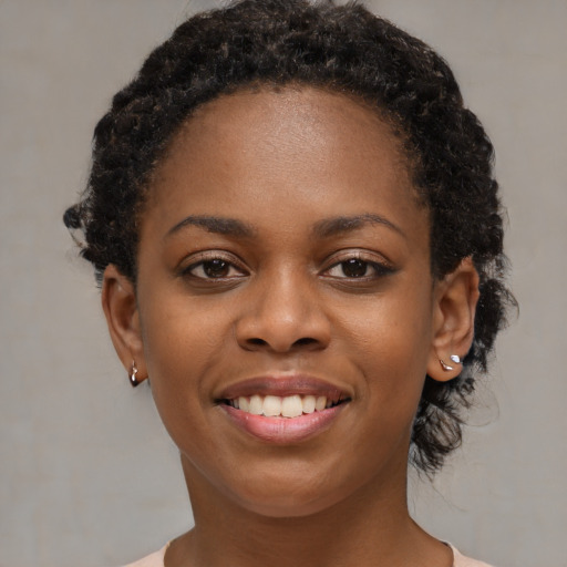 Joyful black young-adult female with short  black hair and brown eyes