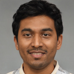 Joyful latino young-adult male with short  black hair and brown eyes