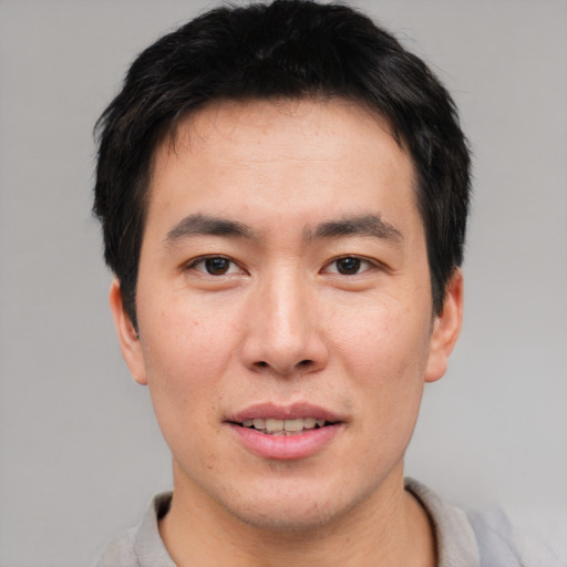 Joyful asian young-adult male with short  brown hair and brown eyes