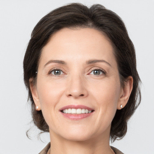 Joyful white young-adult female with medium  brown hair and grey eyes