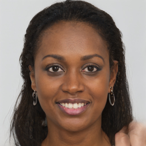 Joyful black young-adult female with long  brown hair and brown eyes
