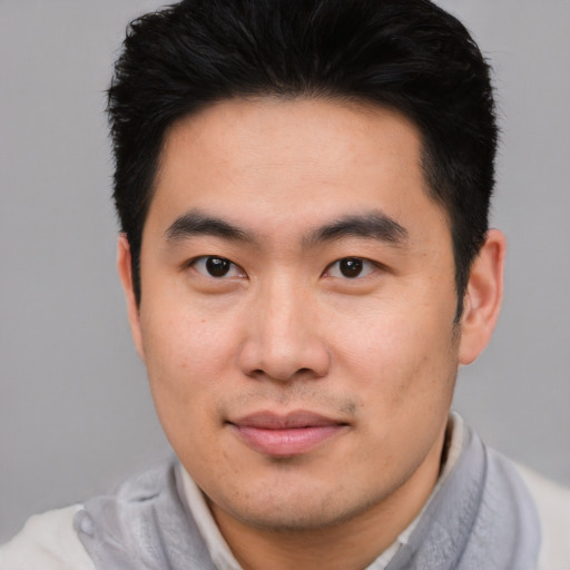 Joyful asian young-adult male with short  brown hair and brown eyes