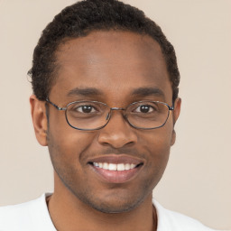 Joyful black young-adult male with short  brown hair and brown eyes