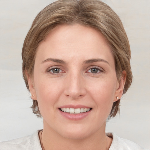 Joyful white young-adult female with medium  brown hair and grey eyes