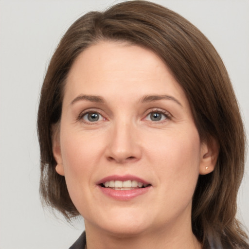 Joyful white young-adult female with medium  brown hair and grey eyes