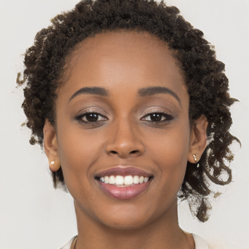 Joyful black young-adult female with long  brown hair and brown eyes