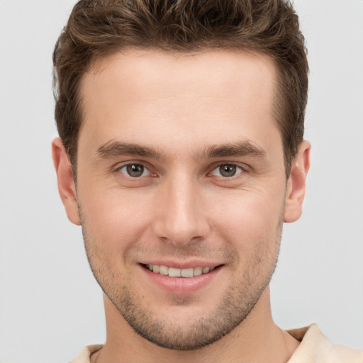 Joyful white young-adult male with short  brown hair and grey eyes