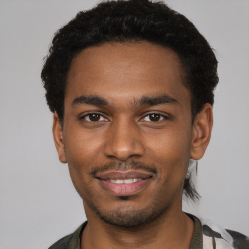 Joyful black young-adult male with short  black hair and brown eyes