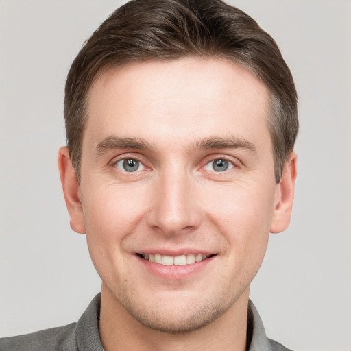 Joyful white young-adult male with short  brown hair and grey eyes