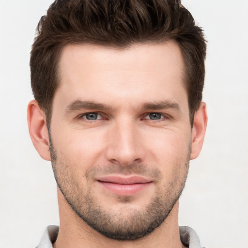 Joyful white young-adult male with short  brown hair and grey eyes