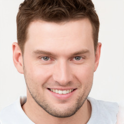 Joyful white young-adult male with short  brown hair and grey eyes