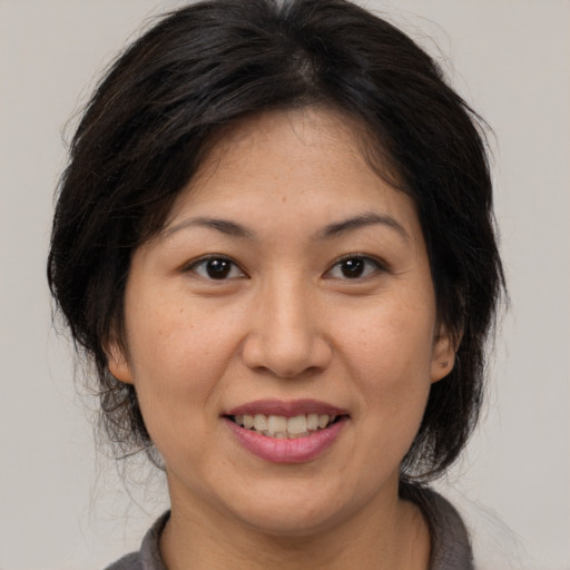 Joyful asian adult female with medium  brown hair and brown eyes
