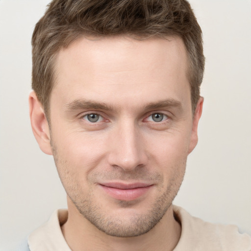 Joyful white young-adult male with short  brown hair and grey eyes