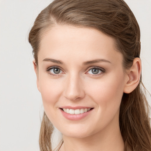 Joyful white young-adult female with long  brown hair and blue eyes