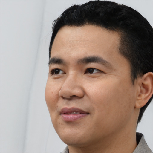Joyful latino young-adult male with short  black hair and brown eyes