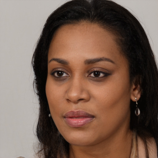 Joyful black young-adult female with long  brown hair and brown eyes