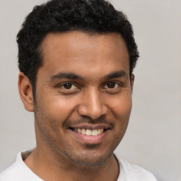 Joyful latino young-adult male with short  black hair and brown eyes