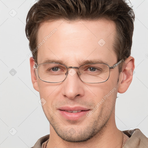 Joyful white young-adult male with short  brown hair and grey eyes