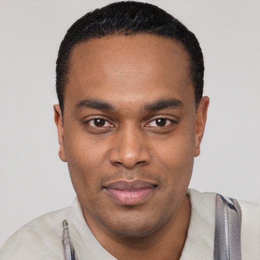 Joyful black young-adult male with short  black hair and brown eyes