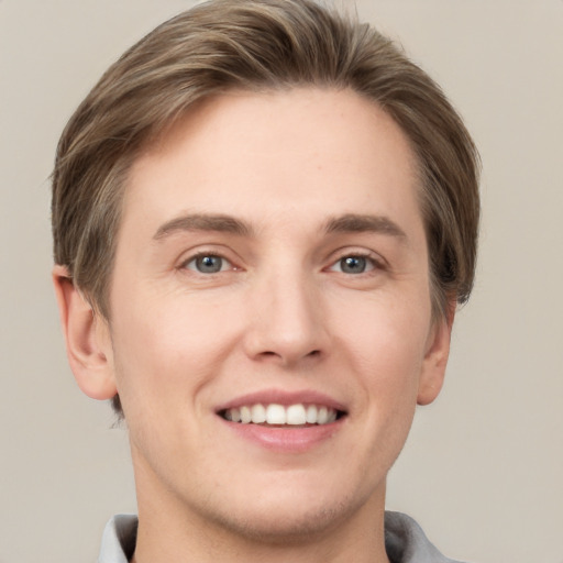 Joyful white young-adult male with short  brown hair and grey eyes