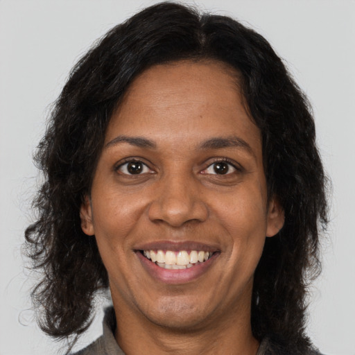 Joyful black young-adult female with long  brown hair and brown eyes