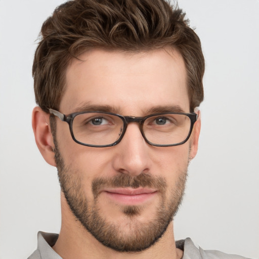 Joyful white young-adult male with short  brown hair and grey eyes