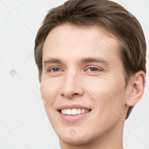 Joyful white young-adult male with short  brown hair and grey eyes