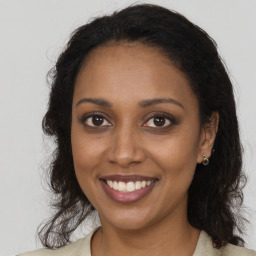 Joyful black young-adult female with long  brown hair and brown eyes