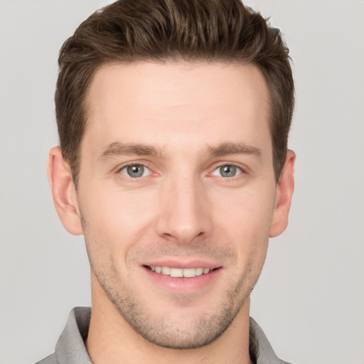 Joyful white young-adult male with short  brown hair and grey eyes