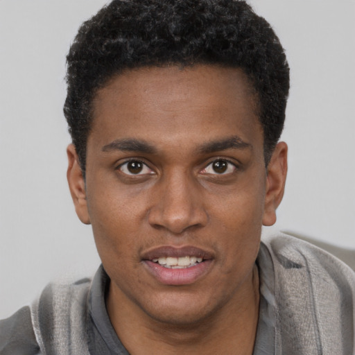 Joyful black young-adult male with short  black hair and brown eyes