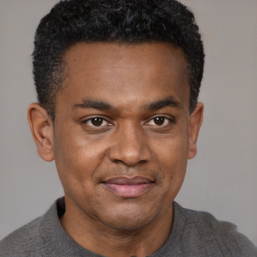 Joyful black young-adult male with short  black hair and brown eyes