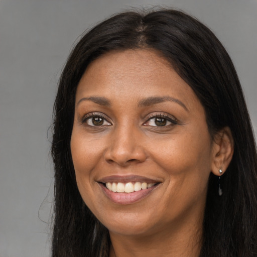 Joyful black adult female with long  brown hair and brown eyes