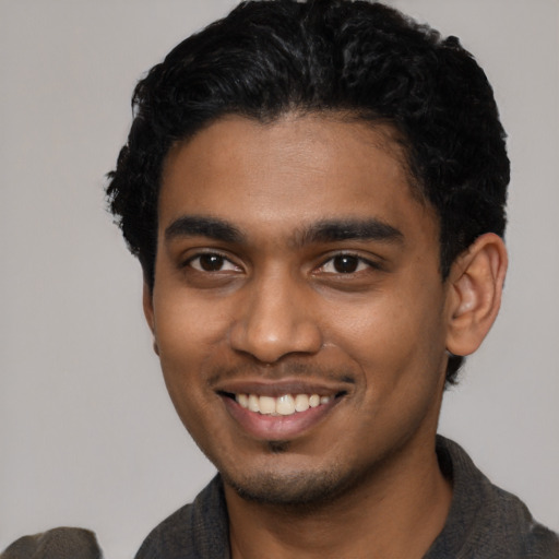 Joyful black young-adult male with short  black hair and brown eyes