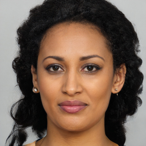 Joyful black young-adult female with long  black hair and brown eyes