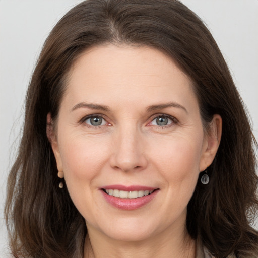 Joyful white adult female with long  brown hair and grey eyes