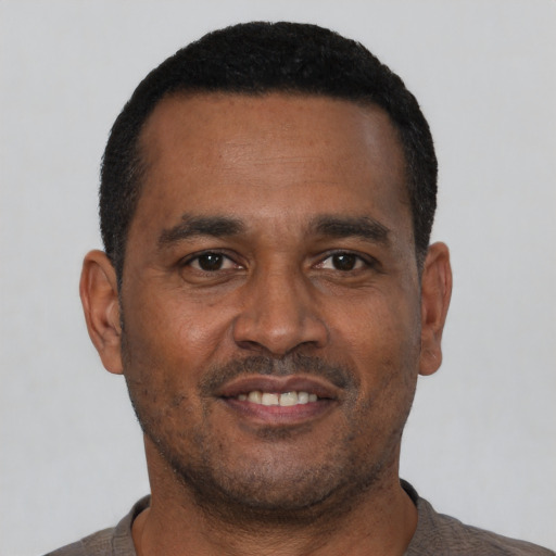 Joyful black young-adult male with short  black hair and brown eyes