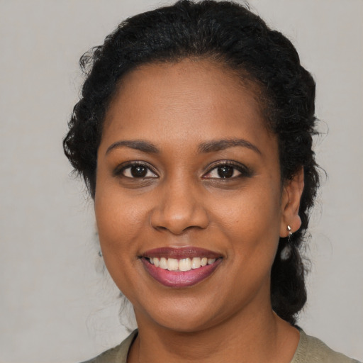 Joyful black young-adult female with long  brown hair and brown eyes
