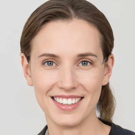 Joyful white young-adult female with medium  brown hair and grey eyes