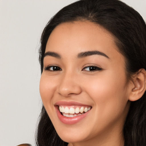 Joyful latino young-adult female with long  brown hair and brown eyes