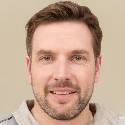 Joyful white young-adult male with short  brown hair and grey eyes