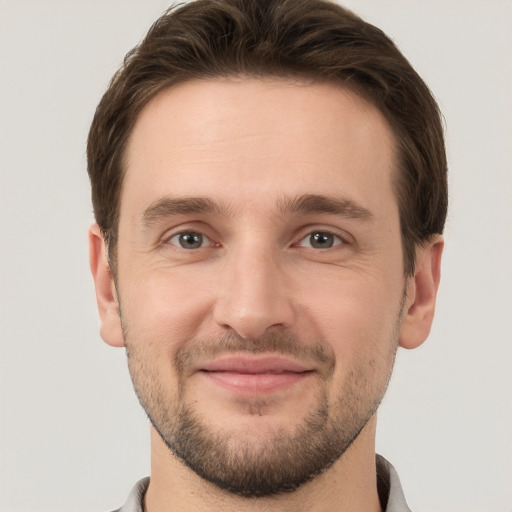 Joyful white young-adult male with short  brown hair and grey eyes