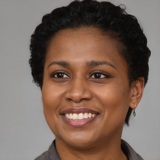 Joyful black young-adult female with short  black hair and brown eyes