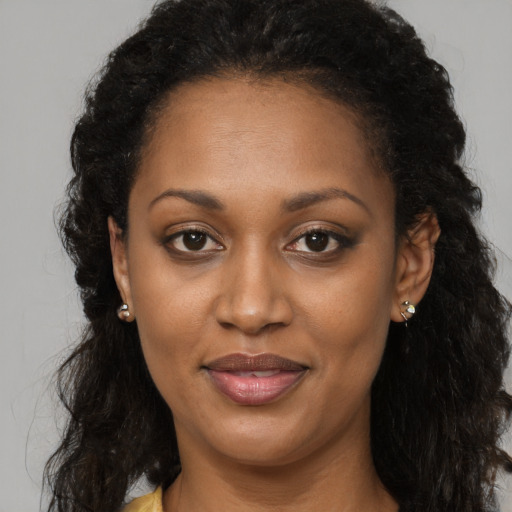 Joyful black adult female with long  brown hair and brown eyes
